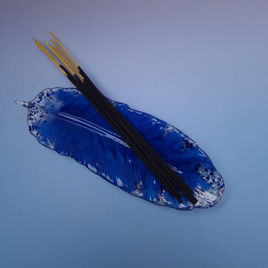 Bandeja de resina epóxi azul em formato de pena usada como suporte para incensos, peça artesanal elegante e decorativa.