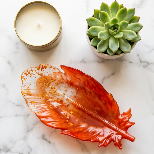 Pena Cobre Maxi em resina epoxy utilizada como prato decorativo para joias, junto a uma vela e uma suculenta, criando um ambiente elegante e acolhedor.