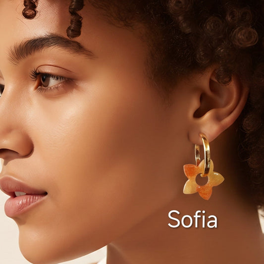 Modelo a usar brincos Sofia em forma de flor, em tons quentes de amarelo e laranja, criados artesanalmente em resina epóxi pela Sweet Art.