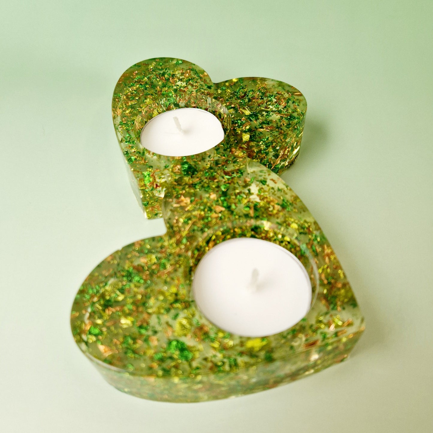 Castiçal duplo em formato de coração em resina epóxi verde translúcida com folhas metálicas douradas, vista superior