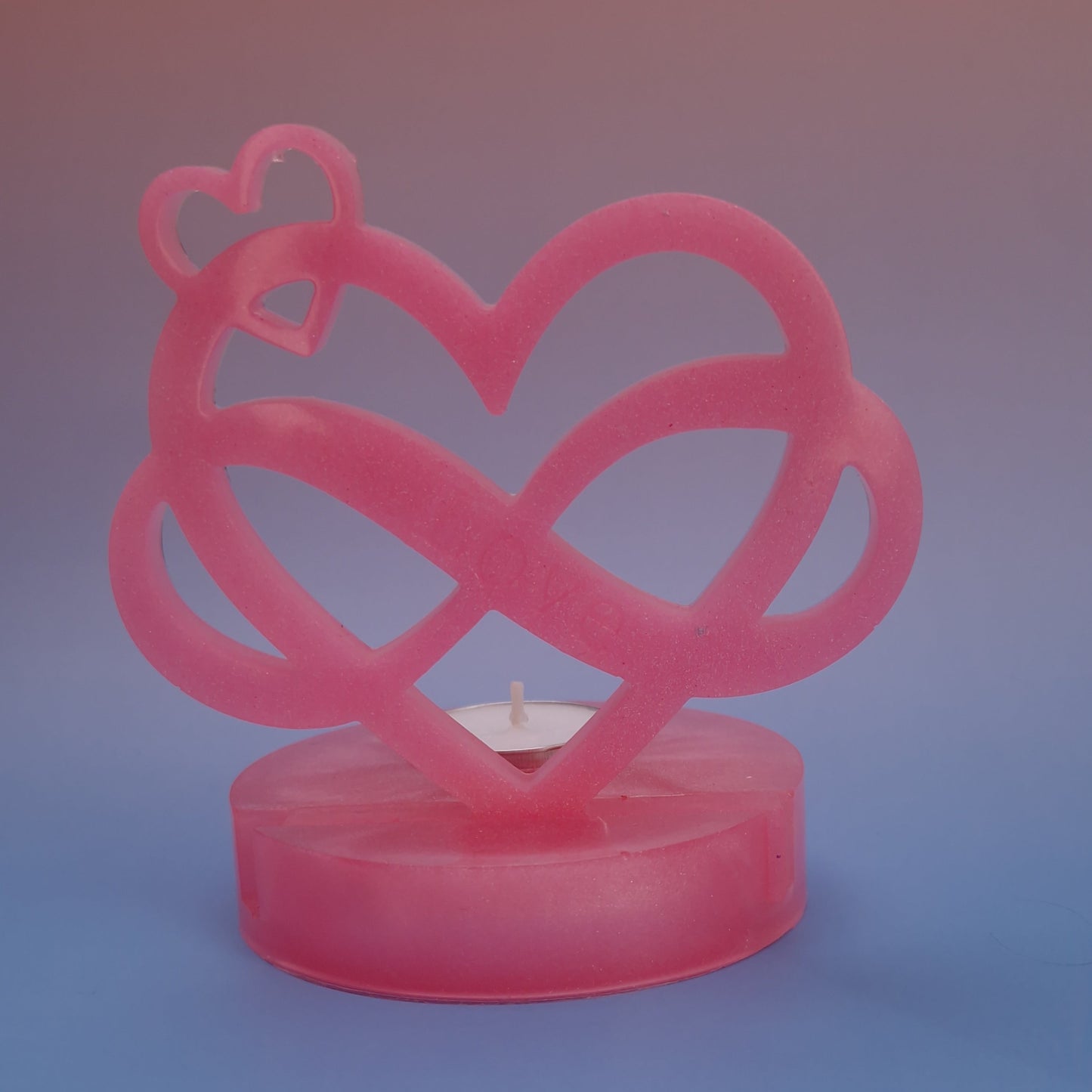 Castiçal decorativo em resina epóxi rosa perolado com design de coração infinito e vela tealight ao centro