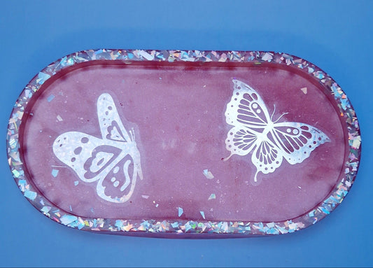 Bandeja decorativa oval em resina epóxi rosa com borboletas brancas e glitters holográficos, vista superior