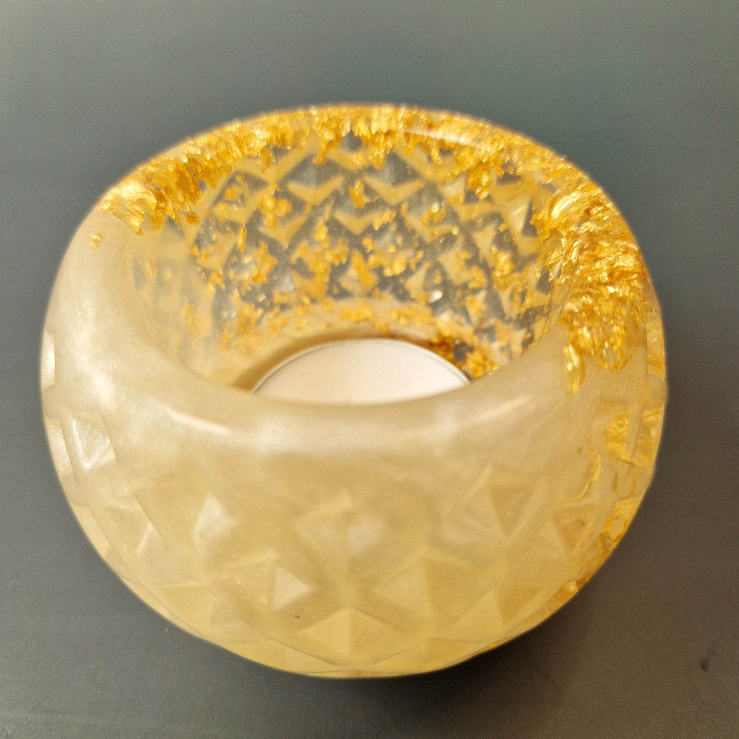 Porta-velas em resina translúcida com acabamento perolado e detalhes em folha dourada, vista lateral superior