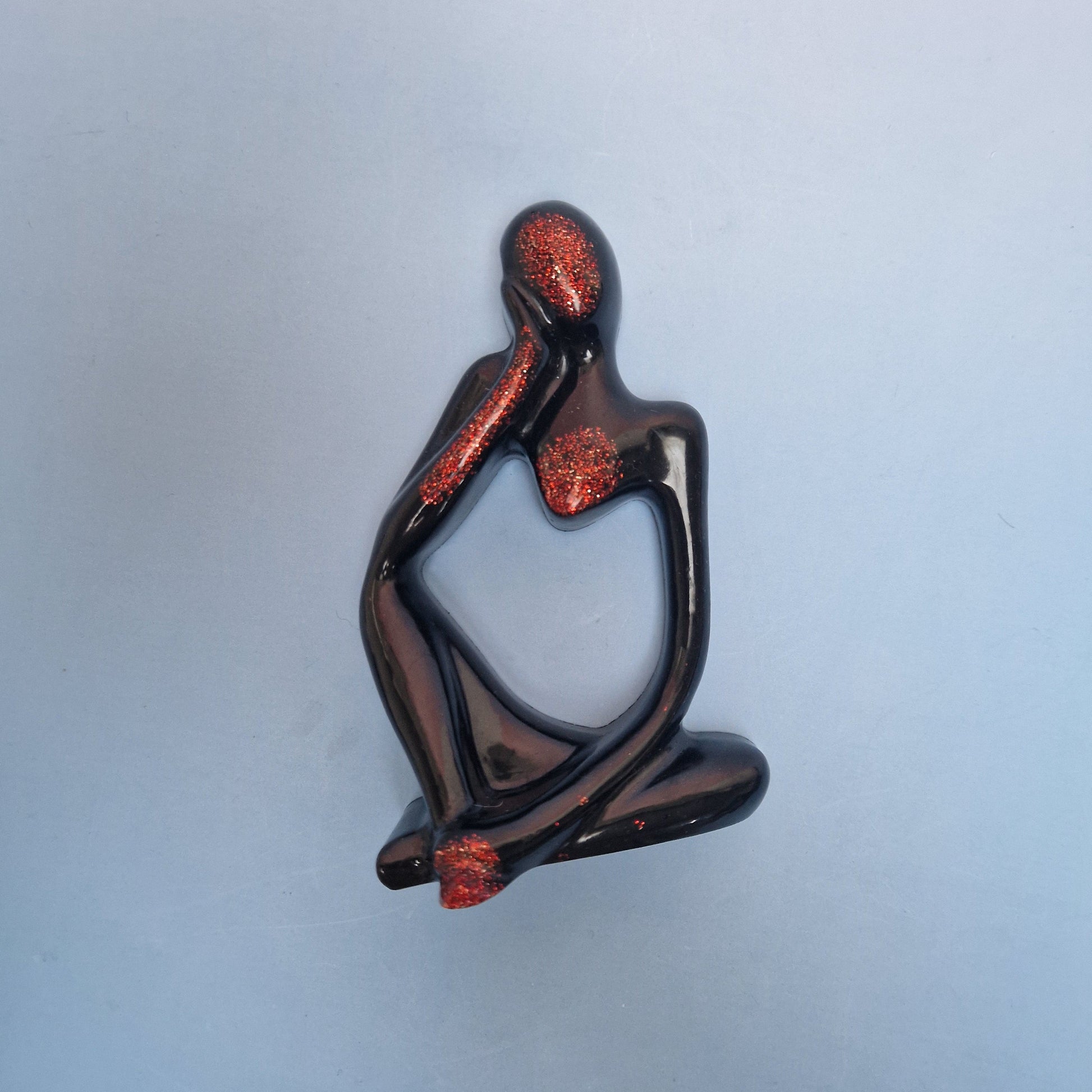 Figura abstrata decorativa em resina epoxy preta com detalhes em purpurina vermelha