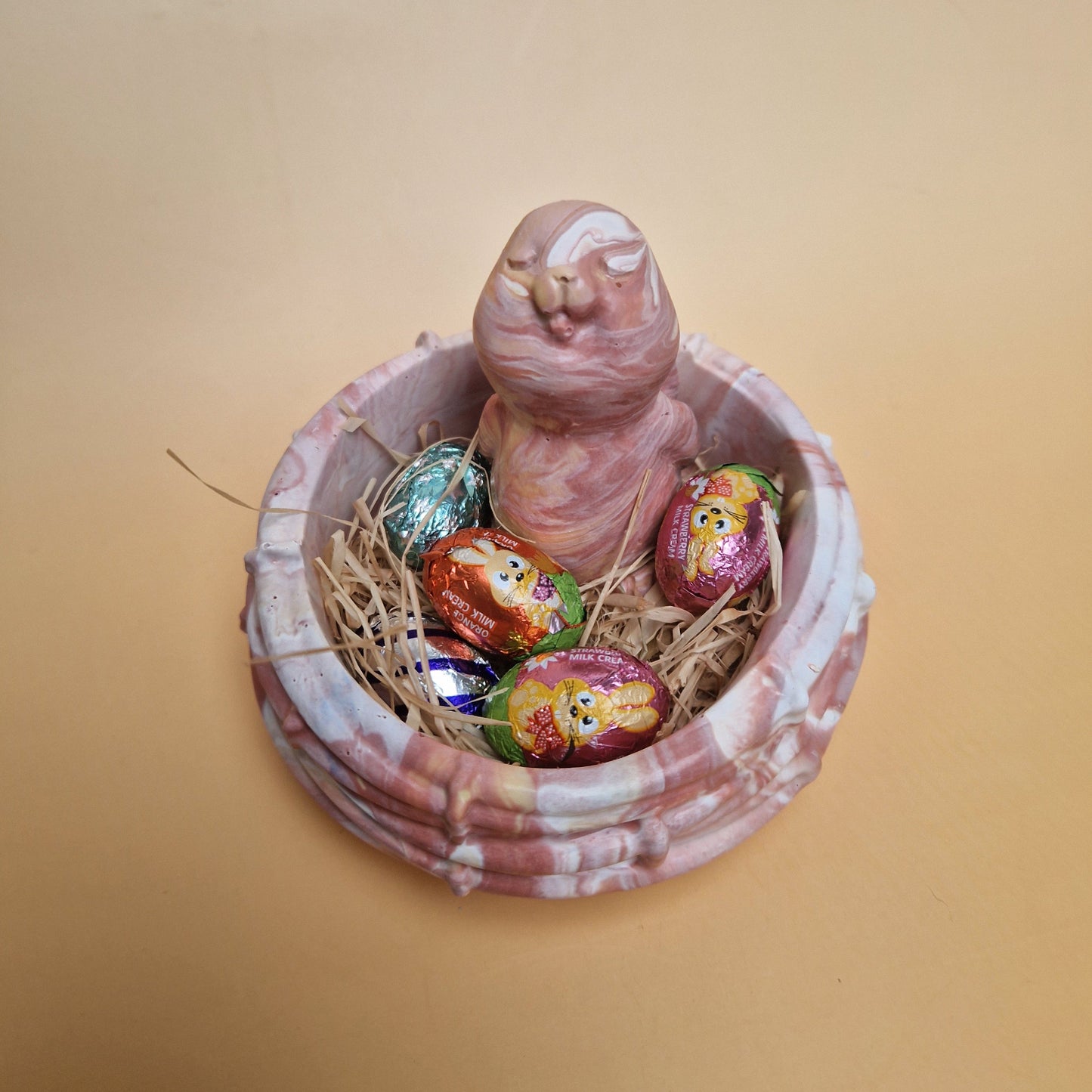 Decoração Páscoa com coelho rosa em Jesmonite dentro de ninho com ovos de chocolate