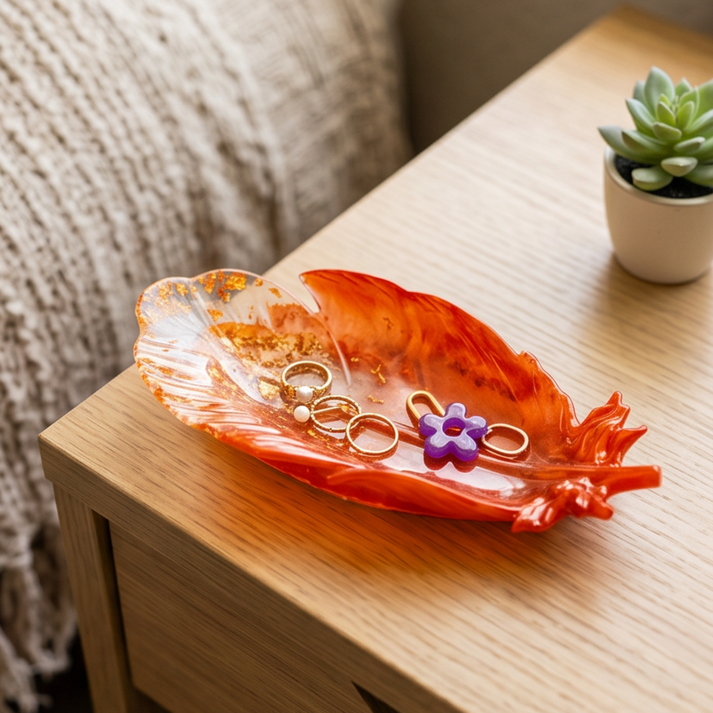 Pena Cobre Maxi em resina epoxy sobre uma mesa de cabeceira, perfeita para organizar anéis, brincos e pequenos acessórios com elegância.