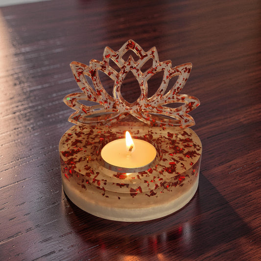 Suporte decorativo em resina com reflexos de folhas metálicas vermelhas sob a luz de uma chama.
