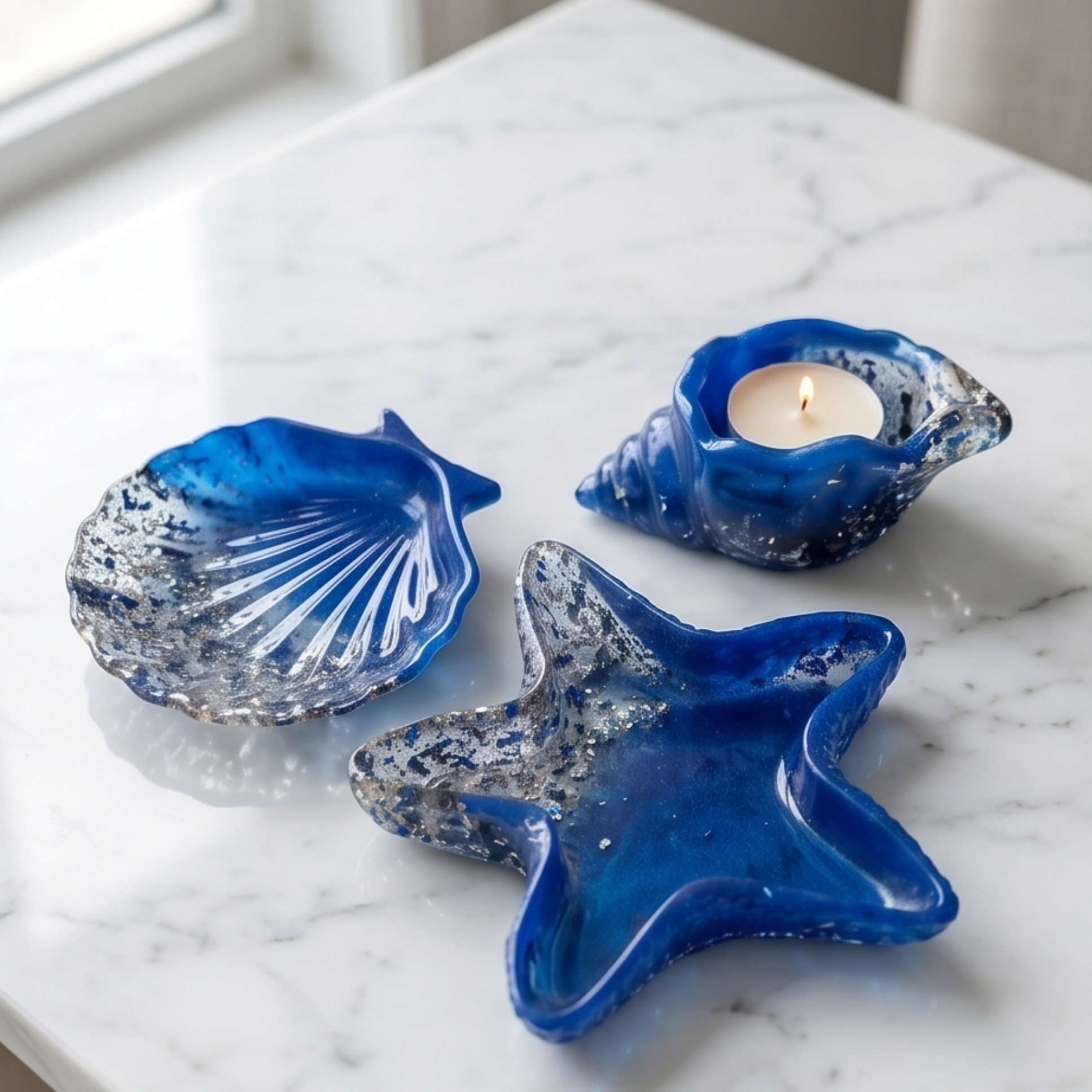 Conjunto decorativo em resina azul com estrela-do-mar, concha e búzio sobre superfície de mármore