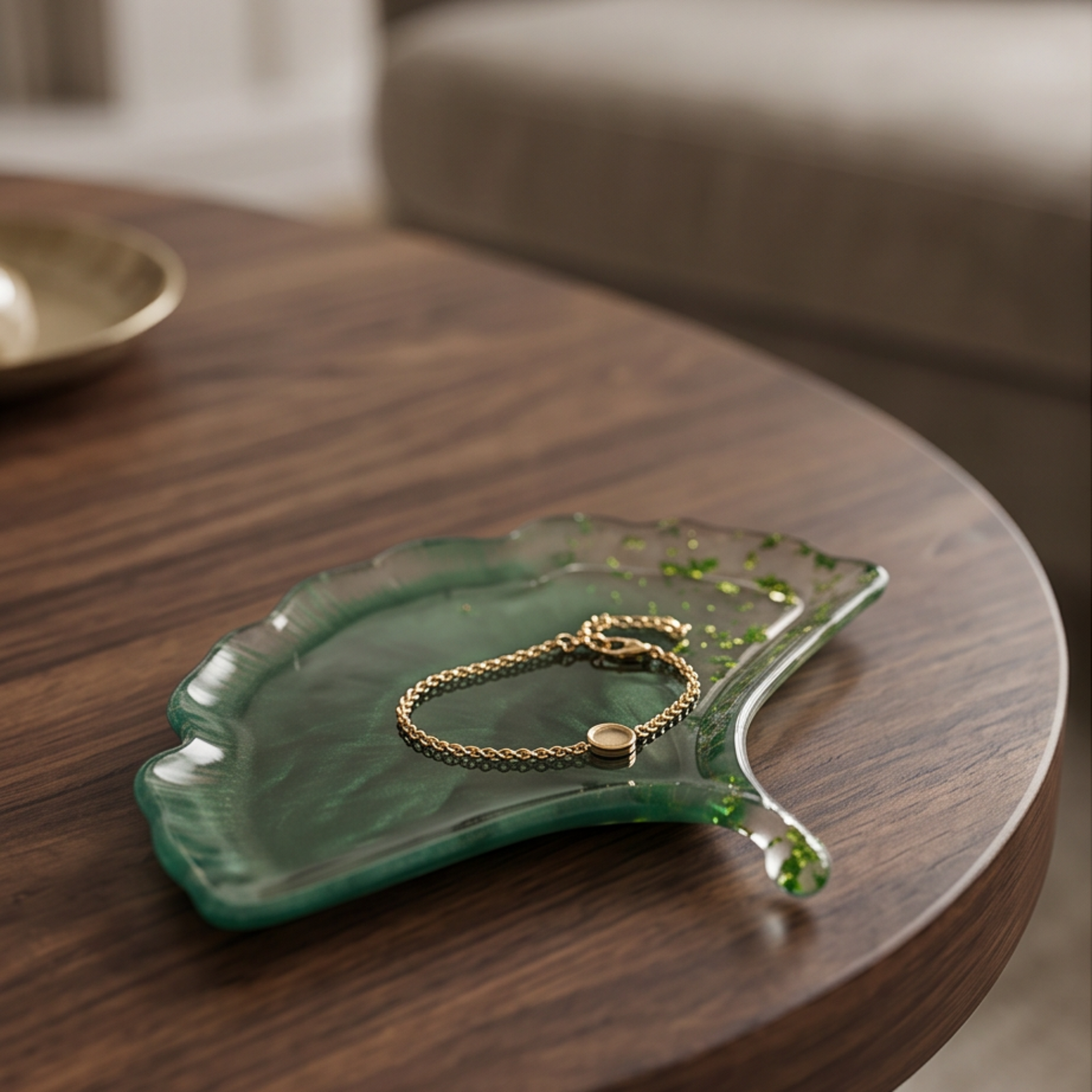 Prato decorativo Ginkgo Esmeralda em resina epóxi artesanal com pulseira dourada sobre mesa de madeira.