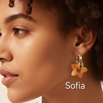 Modelo a usar brincos Sofia em forma de flor, em tons quentes de amarelo e laranja, criados artesanalmente em resina epóxi pela Sweet Art.