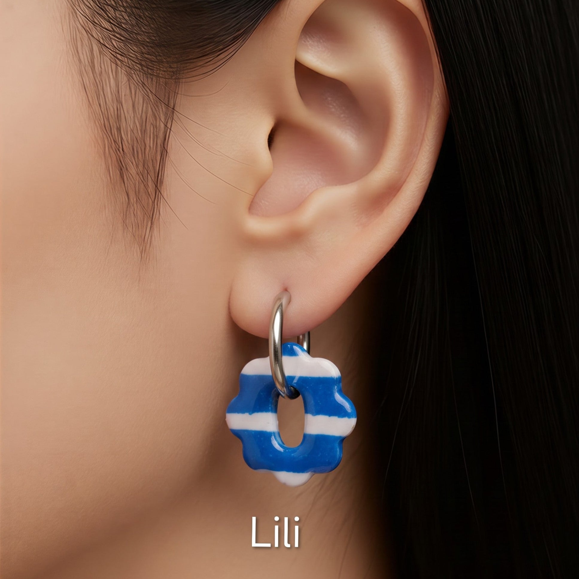 Brincos intercambiáveis Sweet Art com pendentes Lili em argila polimérica azul e branca às riscas, usados com argolas.